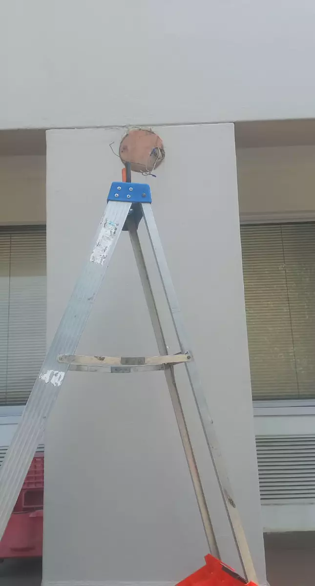 Stepladder in front of a wall with an electrical opening
