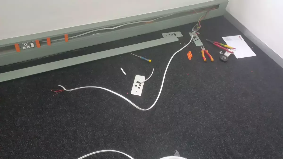 Electrical wiring installation in progress with tools on a carpeted floor