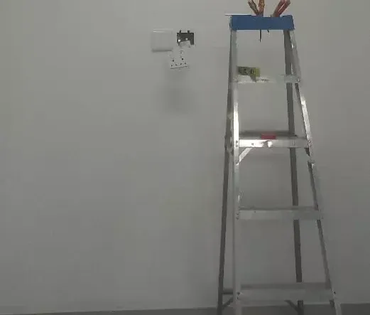 Metal stepladder and electrical outlets on a plain wall